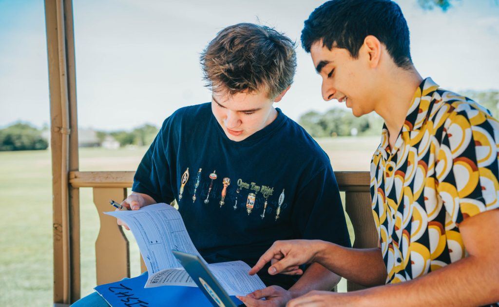 Two students reading together outdoors